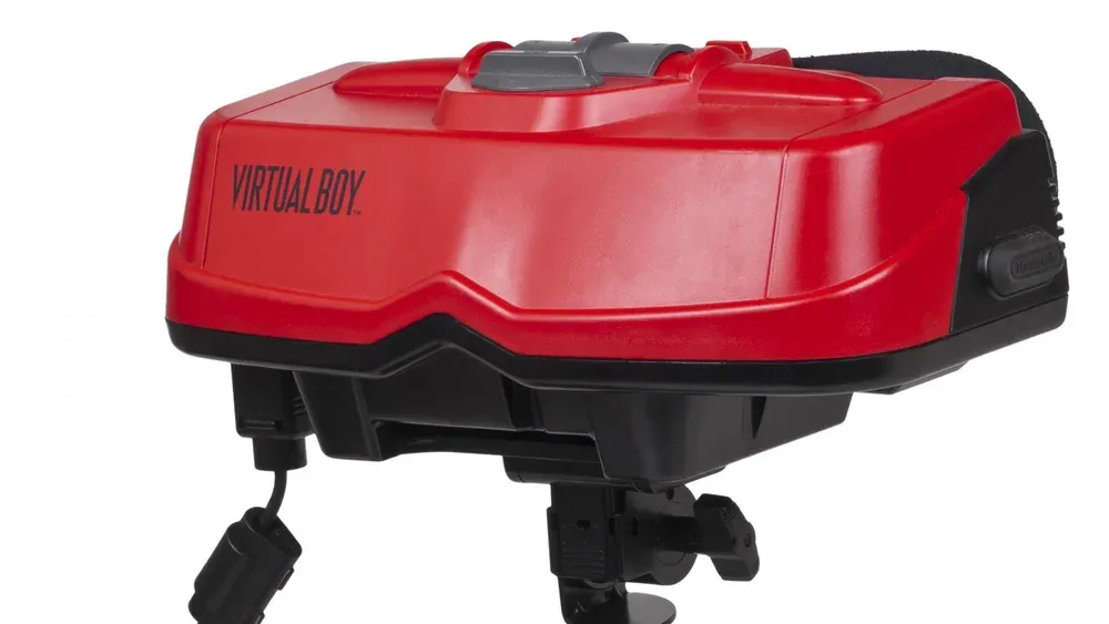 A red plastic gaming device sitting atop a black stand with the words Virtual Boy printed on it.
