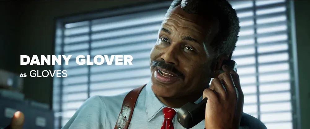 Text: Danny Glover as Gloves. Image shows a digital version of actor Danny Glover talking on a phone in an office.