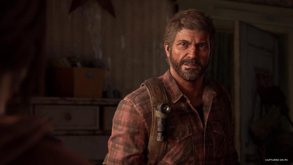 Bearded man in a faded red plaid shirt looking somewhat angry at a person slightly off screen in the foreground.