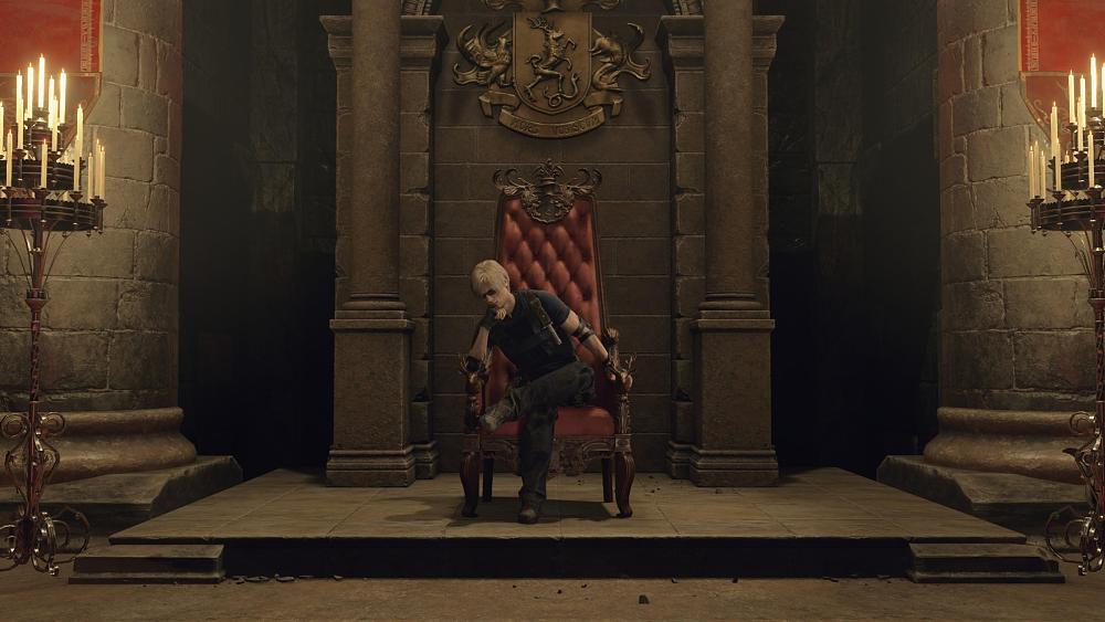 A man with blonde hair, wearing sunglasses, sitting in a plus red makeshift throne. Two tall candle holders flank on either side.