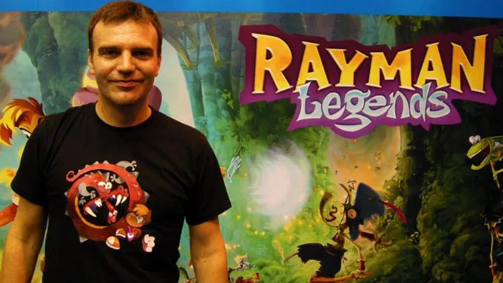 Photo of Emile Morel standing next to a display for Rayman Legends.