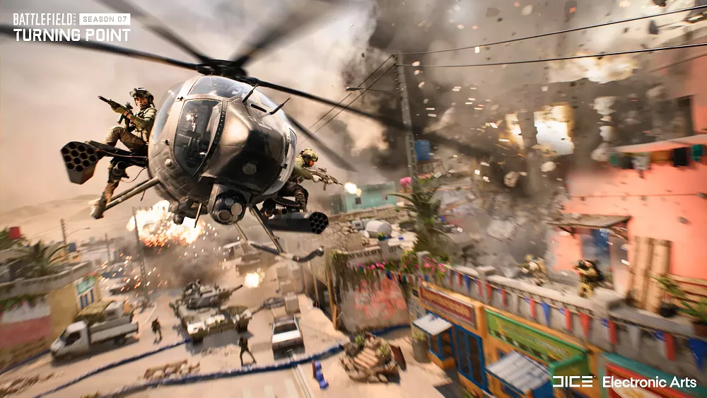 A helicopter flying low over a small city in the middle of a warzone.