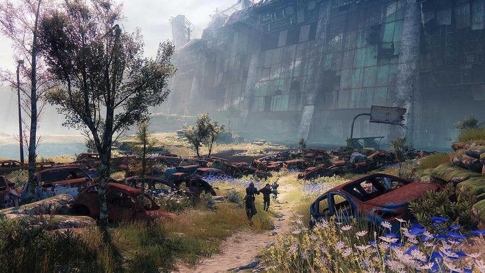 An image of several rusted shells of cars and some Guardians walking amongst them in Destiny 2.